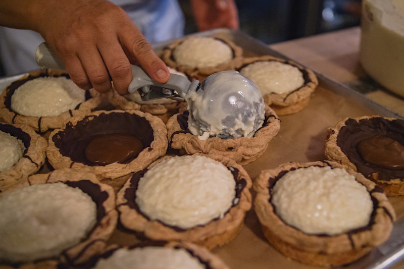 A baker adds filling to tart shells
