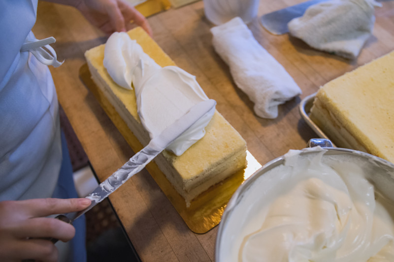 A baker applies icing to a cake