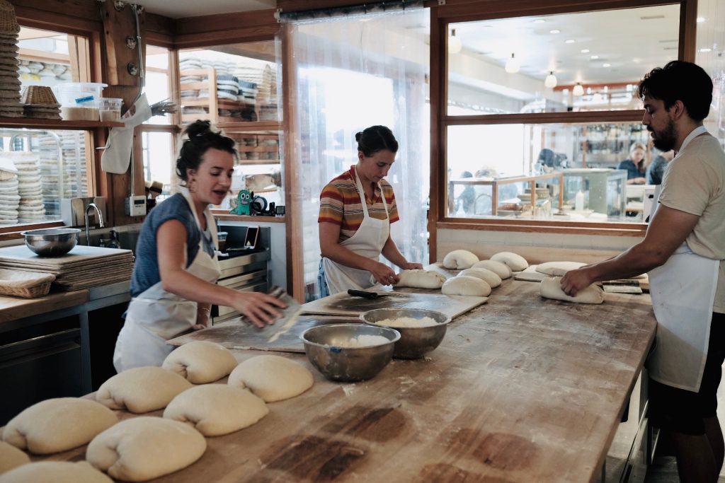 Several bakers knead and shape loaves of bread