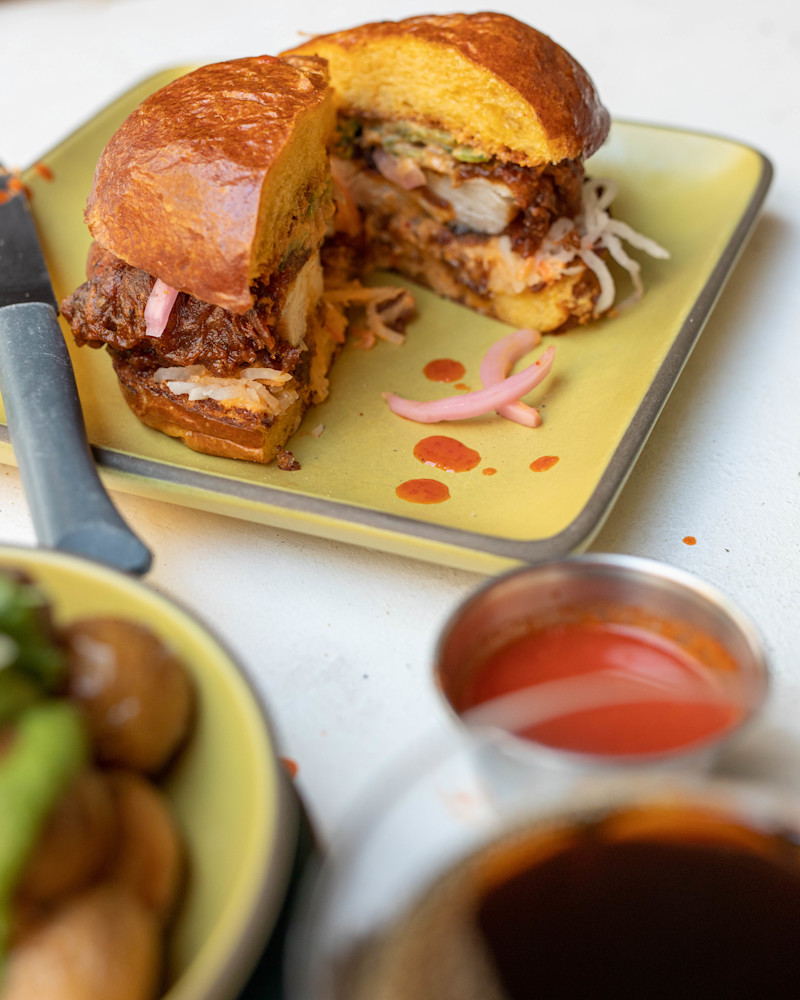 A fried chicken sandwich with a side of hot sauce