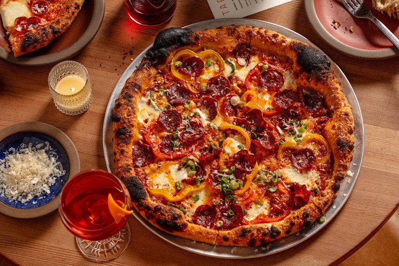 A wonderfully-charred pepperoni alongside a negroni cocktail with an orange twist